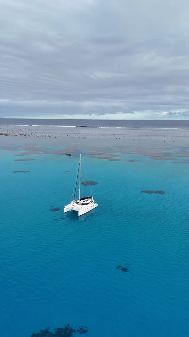 Aerial of Mā Tori anchored on the edge of a Fijian reef