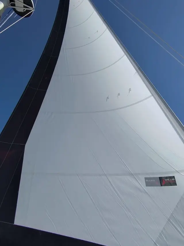 Mā Tori's mainsail full and drawing against a clear blue sky