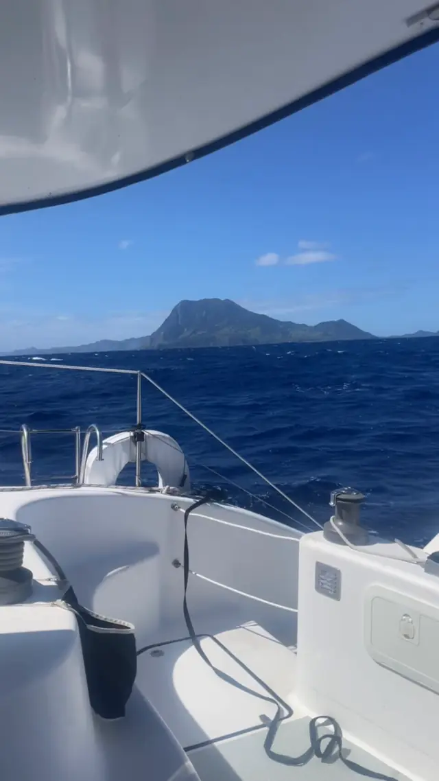 A volcanic island rising over the bow as Mā Tori makes landfall under sail