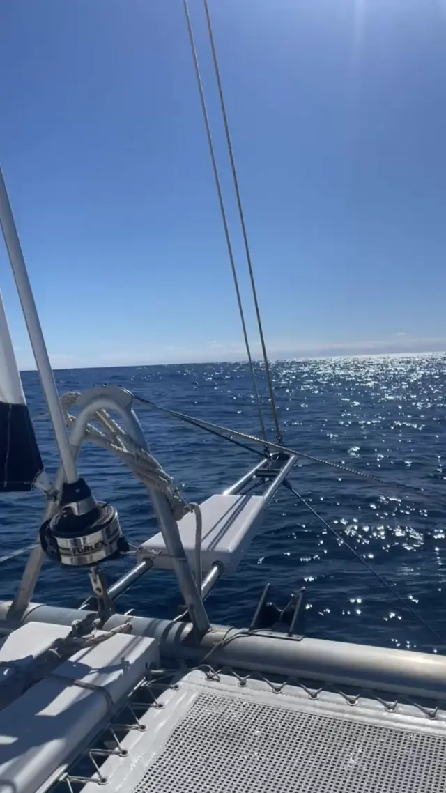 Rig and trampolines of Mā Tori sailing across a sparkling sea