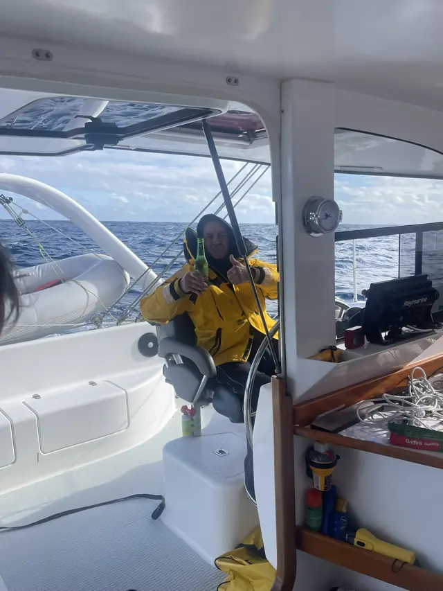 Crew in wet weather gear on watch at the helm offshore