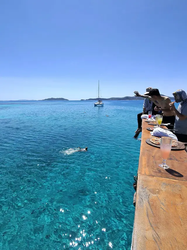 Snorkelling the reef in crystal clear Fijian water with a yacht anchored beyond
