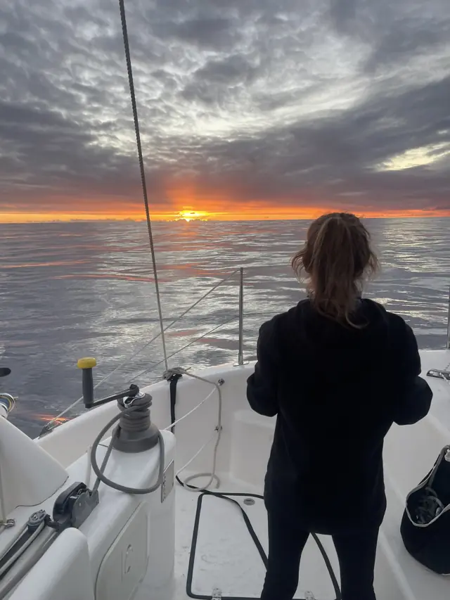 Helm watch at sunset aboard Mā Tori