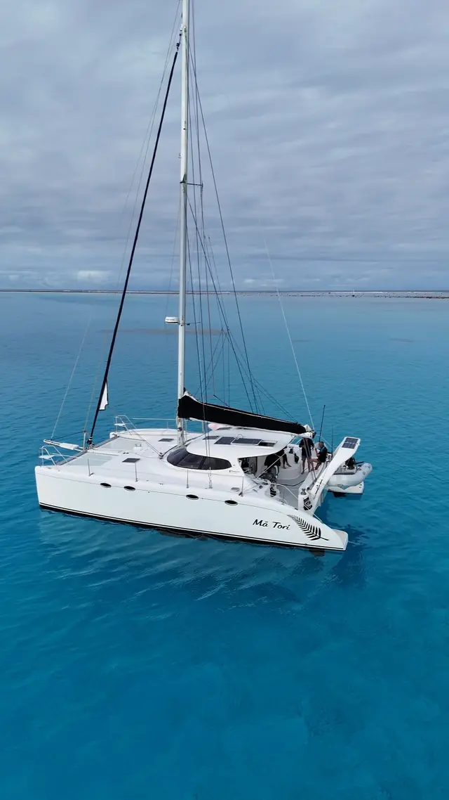 Aerial view of Mā Tori anchored on a turquoise Fijian reef flat