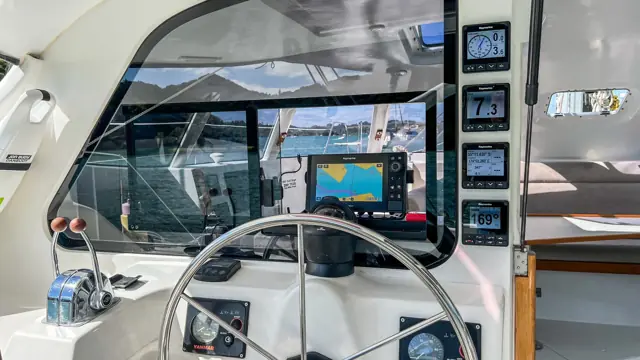 Wheel and Raymarine chartplotter at the helm of Mā Tori